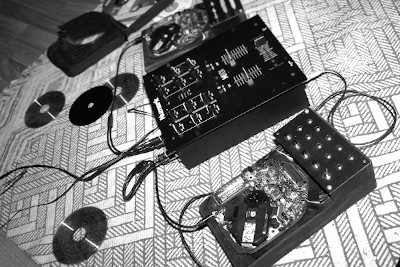 black and white image of two cd players with a dj mixer with some green highlights